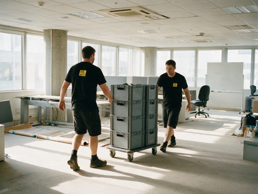 Crew wheeling stacked IT crates through an open plan office